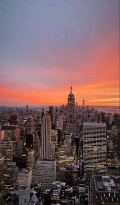 the city skyline is lit up at night with bright orange and pink colors in the sky