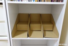 four boxes are stacked on top of each other in a shelf next to some books