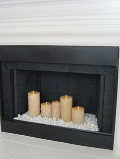 some candles are sitting in front of a fire place