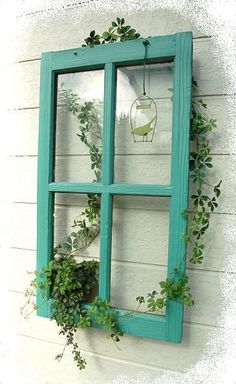 an old window is decorated with greenery and hanging from the side of a house