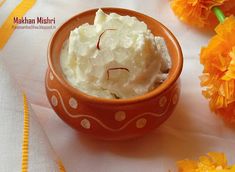 a bowl filled with whipped cream sitting on top of a table next to orange flowers