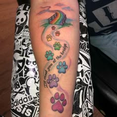 a person with a tattoo on their arm that has paw prints and a rainbow kite