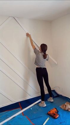 a woman is painting the walls in an empty room