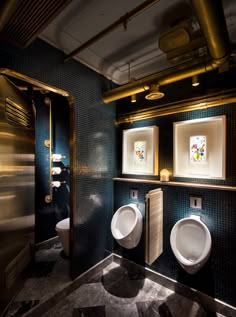 two urinals in a public restroom with gold trim and blue tiles on the walls