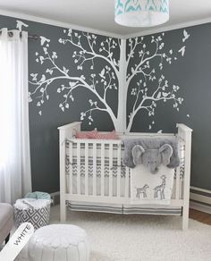 a baby's room with a tree decal on the wall and an elephant crib