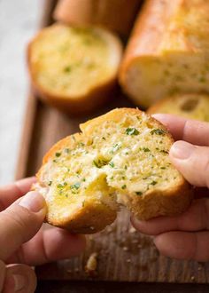 someone holding up a piece of bread with cheese and herbs on it in their hands