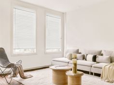 a living room with white furniture and windows covered in blind shades on the window sill