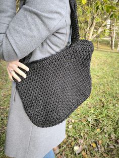 a woman carrying a crocheted black bag