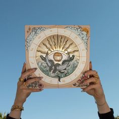 two hands holding up a paper with an image of a sun and moon on it