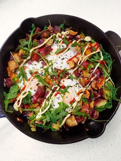 a skillet filled with lots of food on top of a white counter next to a knife