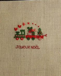 a cross stitch christmas card with a train and trees on the front in red, green and white