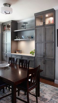 a dining room table and chairs in front of an open kitchen area with built - in cabinets