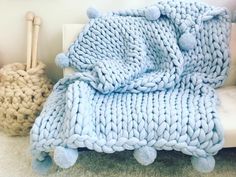 a blue blanket sitting on top of a white couch next to a pile of blankets