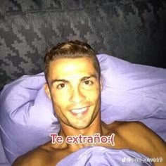 a shirtless man laying in bed with purple sheets on his chest and smiling at the camera