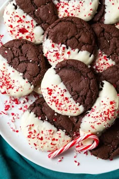 chocolate cookies with white frosting and candy canes on a plate, ready to be eaten