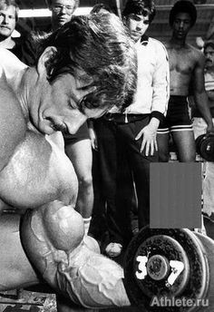 a man squatting down in front of a group of men with dumbbells