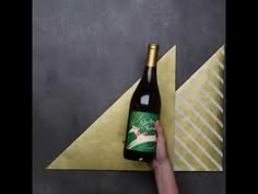 a hand holding a bottle of beer next to a piece of paper with an origami design on it