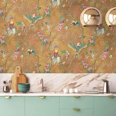 a kitchen with green cabinets and gold wallpaper on the walls, two lights above the sink