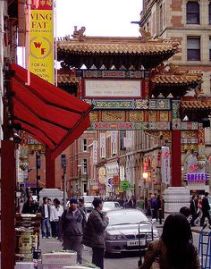 people are walking down the street in front of stores and buildings with red awnings