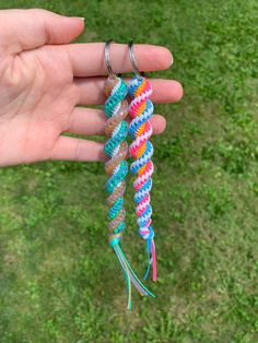 a hand holding three different colored bracelets in it's palm, with grass in the background