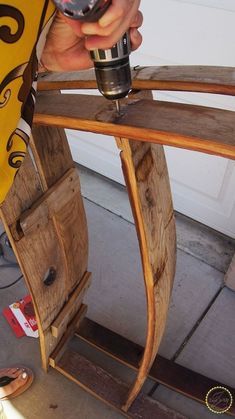 a person holding a drill in their hand near a wooden stand with drawers on it