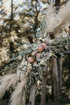 an arrangement of flowers and feathers on a wooden post