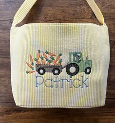 a bag with a tractor and carrots embroidered on the front, sitting on a wooden surface