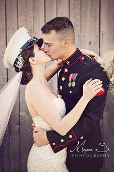 a bride and groom kissing in front of a wooden wall