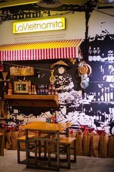 the interior of a restaurant with wooden tables and stools in front of a large mural