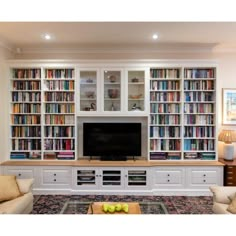 a living room filled with furniture and a flat screen tv sitting on top of a book shelf