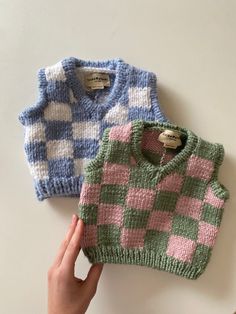 two knitted sweaters sitting next to each other on top of a white table