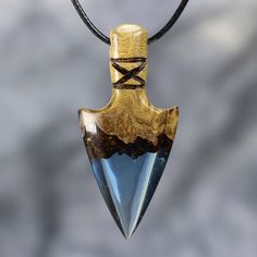 a wooden pendant with a blue stone in the shape of a shield hanging from a leather cord