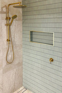 a shower head and hand shower in a bathroom with blue tile on the wall behind it