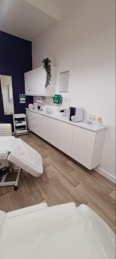 a room with white furniture and blue walls in the center is an office chair, desk, cabinets, and mirror