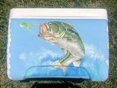 a painting of a large mouth bass catching a green fish on a blue and white cooler