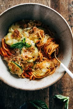 a bowl filled with pasta and sauce on top of a wooden table