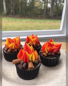 four cupcakes decorated with orange and yellow flowers