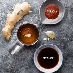 three different types of sauces in small bowls on a table with ginger, garlic and sriraca