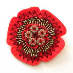 a red flower brooch sitting on top of a white table