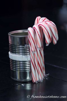 some candy canes are in a metal cup