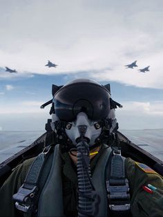 a fighter jet flying over the ocean while wearing a pilot's mask