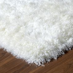 a white shaggy rug on top of a wooden floor