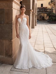 a woman in a white wedding dress standing next to a stone wall with the words pronov