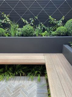 a wooden bench sitting next to a planter filled with plants