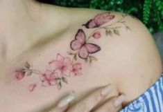 a woman's breast with pink flowers and butterflies on it, as well as a butterfly tattoo