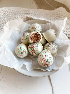 a white plate topped with lots of cake truffles covered in sprinkles