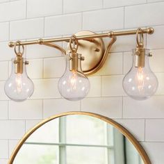 a bathroom light with three bulbs hanging from it's side and a round mirror on the wall