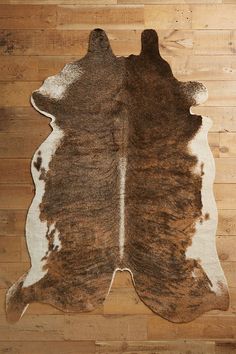 a brown and white cowhide rug sitting on top of a wooden floor