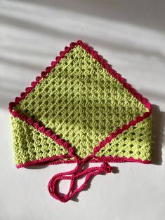 a crocheted green and pink hat sitting on top of a white surface