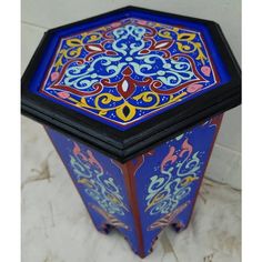 a blue and red box with designs on the lid sitting on a white tile floor